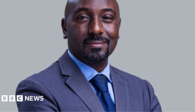 Edward Rukidi Kijanangoma wearing a dark suit and tie smiling