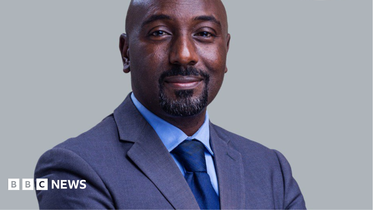 Edward Rukidi Kijanangoma wearing a dark suit and tie smiling