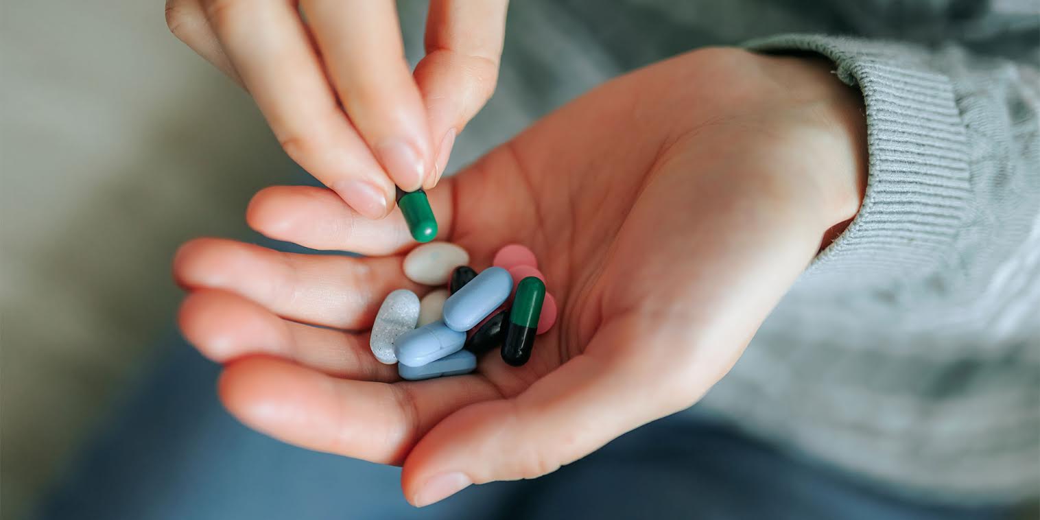 A woman holding lots of supplements in her palm
