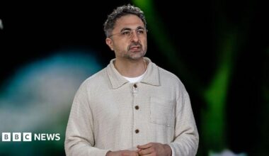 Microsoft's head of AI, Mustafa Suleyman, on stage and wearing a cream top with a collar and a white t-shirt.
