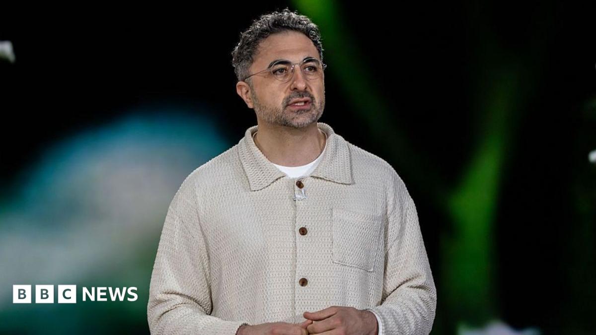 Microsoft's head of AI, Mustafa Suleyman, on stage and wearing a cream top with a collar and a white t-shirt.