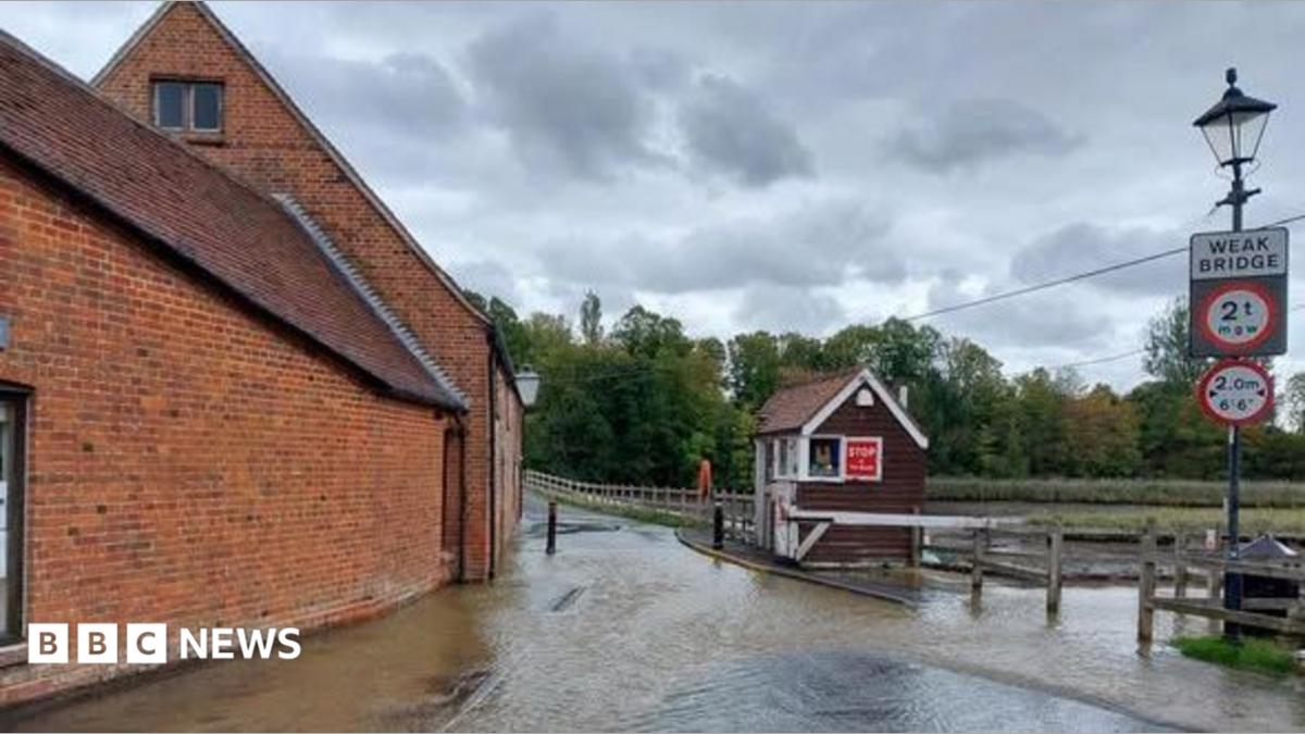 Totton Tide Mill area flooded after a burst water main.  Brick building to the left , wooden hut for toll bridge and wooden fence to the left.
