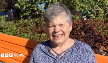 Older woman in a black and blue top on an orange bench