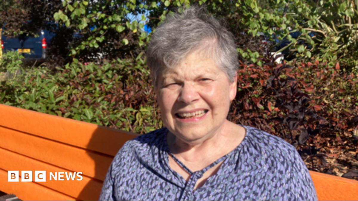 Older woman in a black and blue top on an orange bench