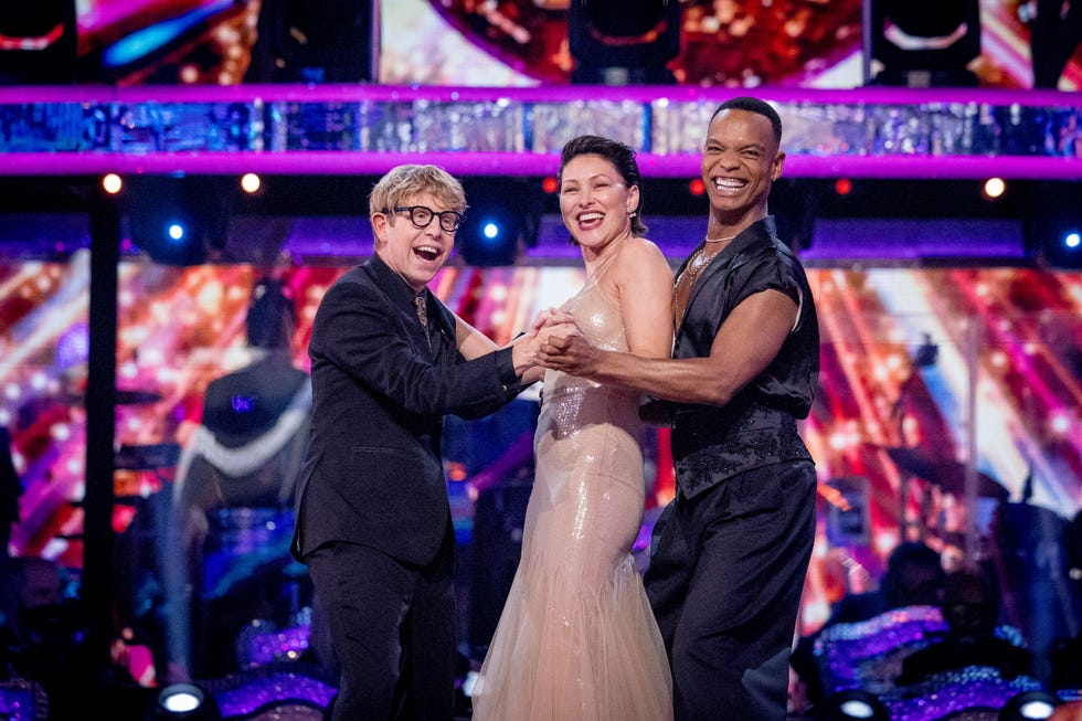 strictly come dancing josh emma johannes EMBARGOED UNTIL 9.15pm three people smiling and holding hands on a colorful stage.