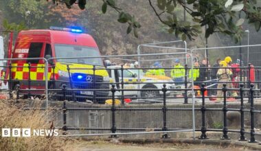 At least a dozen emergency service workers on the river bank in Sunderland, with a water rescue unit van in the foreground. There is temporary fencing around the area. Many of the emergency staff are wearing yellow high-viz jackets and helmets.