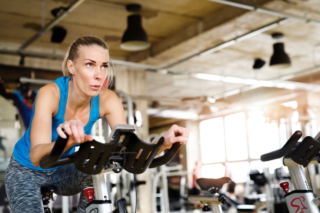Woman cycling on a stationary bike in a gym.