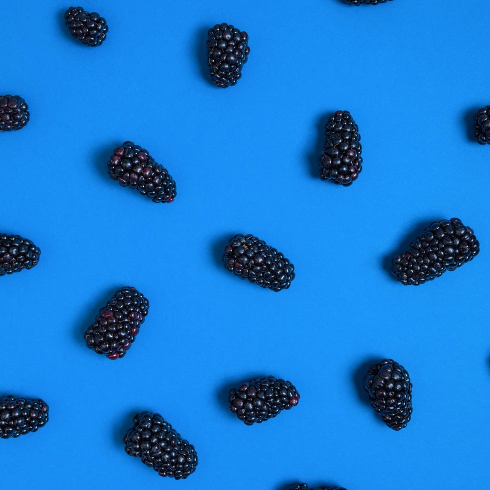 Blackberries Scattered Randomly on Bright Blue Background fresh blackberries scattered in an organic, random pattern on a vivid blue background. modern minimal food concept with high contrast and clean flat lay composition.