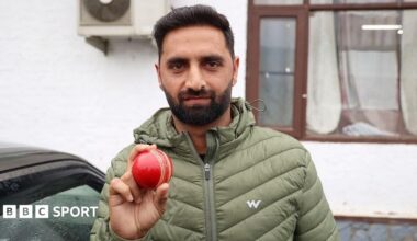 Auqib Nabi holds up a red ball