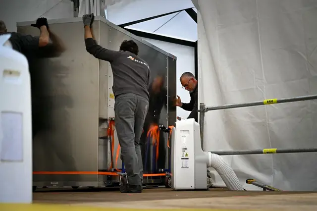 Workers move a fake Bayeux tapestry box into a special conservation equipment, as part as a transport exercice, in Bayeux, northern France, on April 15, 2026.