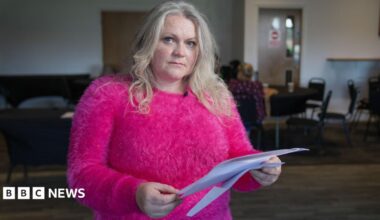 Sam, a resident of Thornton-Cleveleys, holds the blood test results printed on a white piece of paper. She is wearing a bright pink top.