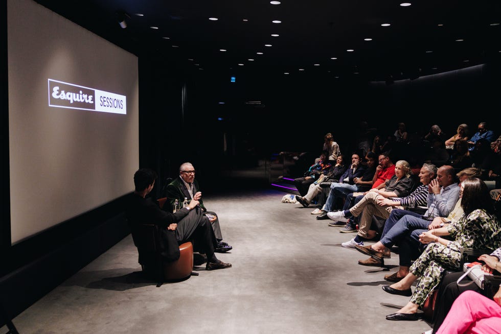 audience attending an esquire sessions event with two speakers on stage in a dark room.