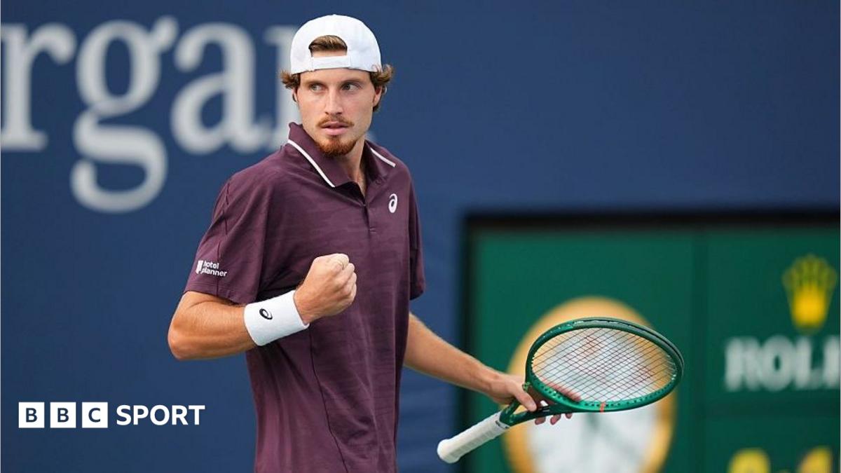 Toby Samuel clenches his fist while on court holding a green tennis racquet