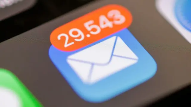 Photo of Email app icon on iPhone screen showing a very full inbox count notification