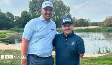 Marcus Armitage is wearing a sky blue polo shirt and a white cap. Adam Dalton Dalton is standing beside him wearing a navy blue cap and a navy blue polo shirt.