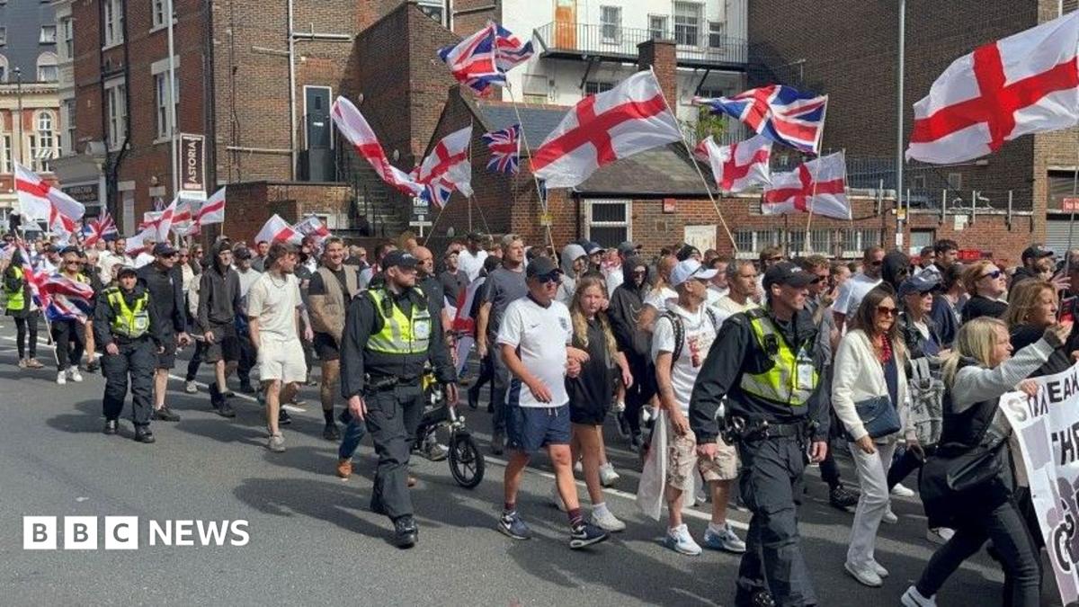 Anti-migration protesters waving St George flags and flanked by police officers