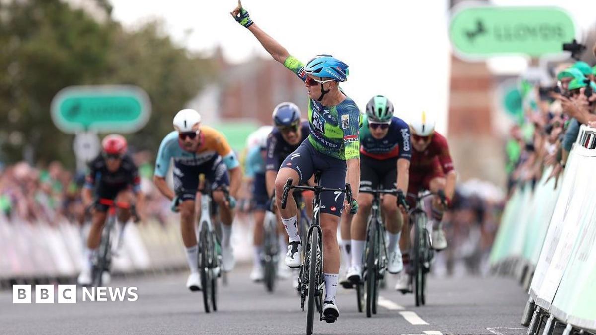 Racer Tim Merlier points a finger in the air to celebrate winning a stage at the Tour of Britain