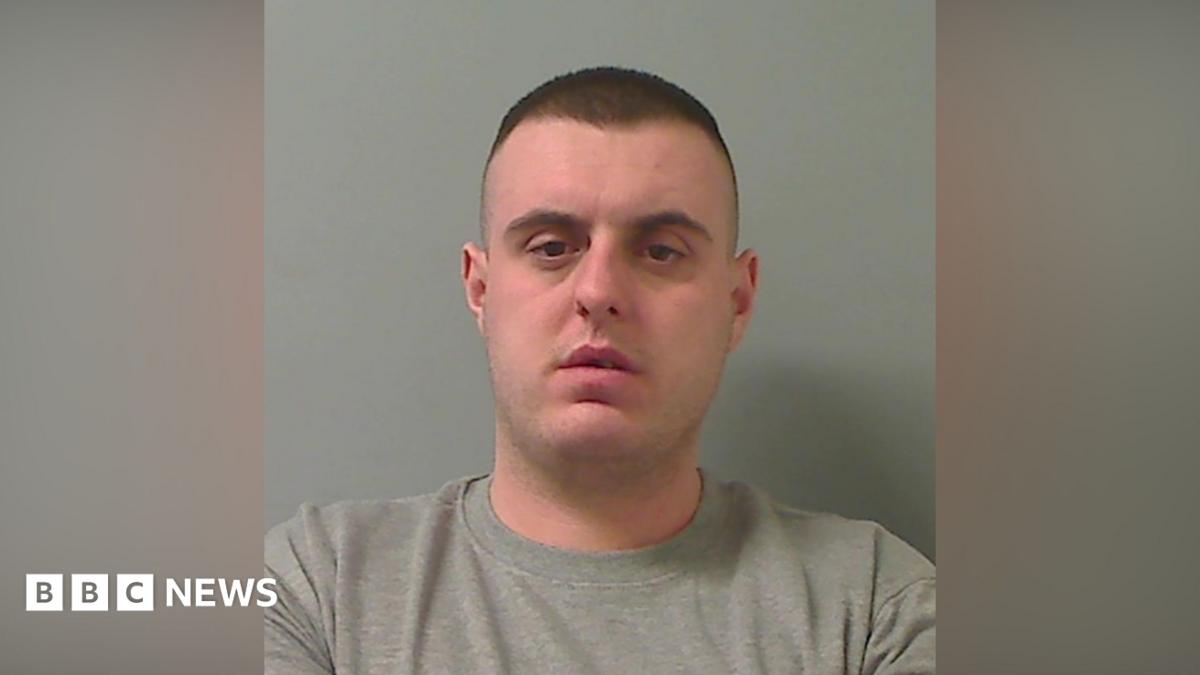 Mugshot of man with short dark hair and a grey sweater