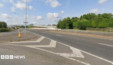A dual carriageway with a large silver bridge photographed from a junction