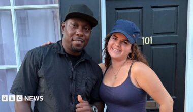 Dizzee Rascal, in black shirt and cap, poses with Ashley, who is wearing a purple summer top and cap.
