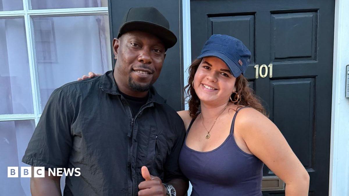 Dizzee Rascal, in black shirt and cap, poses with Ashley, who is wearing a purple summer top and cap.