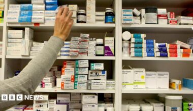 A pharmacist stocking shelves at a chemist.