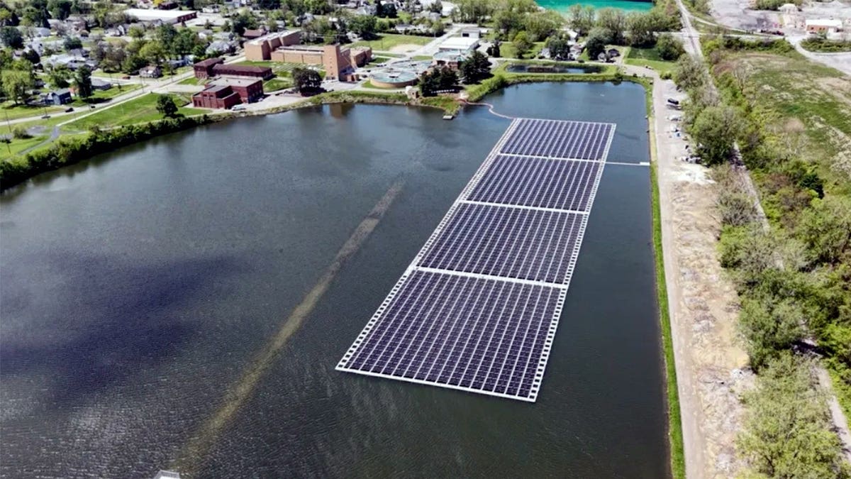 Floating solar panels sit on a body of water.