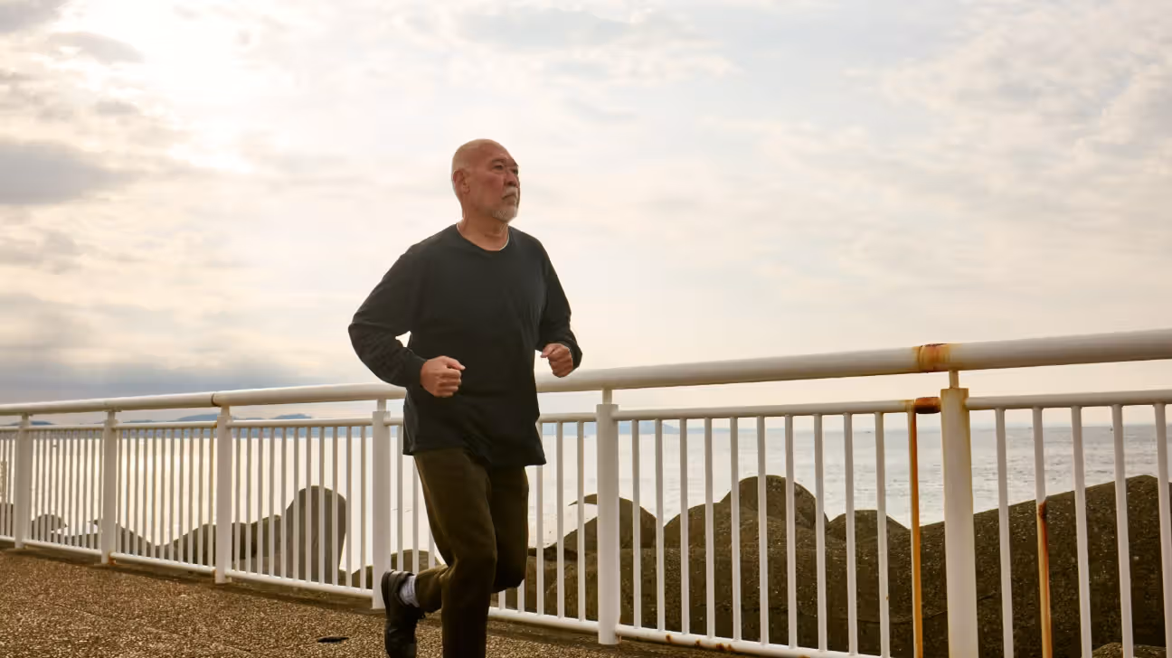 Older male jogging outdoors by water