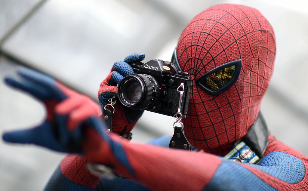 A visitor in a costume of fictional superhero Spiderman takes pictures during the Leipzig Book Fair on March 14, 2015.