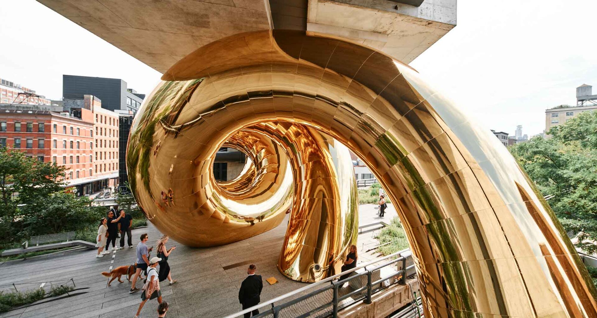 a giant inflatable sculpture of a gold spiral wedged beneath an overpass on the High Line in Manhattan