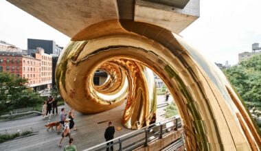 a giant inflatable sculpture of a gold spiral wedged beneath an overpass on the High Line in Manhattan