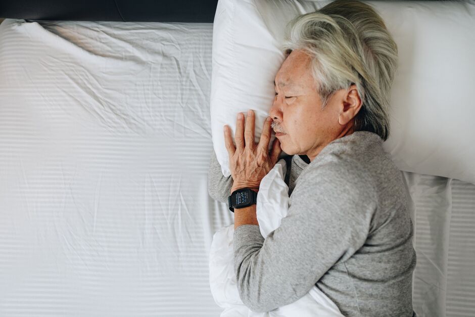 Senior sleeping peacefully while tracking sleep quality with smartwatch wearable technology