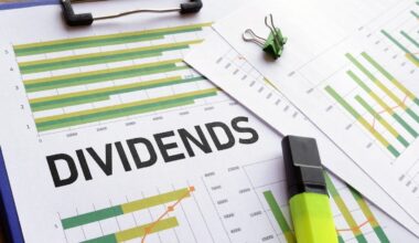 A close-up shot of financial documents on a blue clipboard, with the word 'DIVIDENDS' in large black letters across the center. Several green and yellow bar graphs, some with orange line overlays, are visible on the papers. A green binder clip is on the top right paper, and a bright yellow-green highlighter rests on the bottom right.