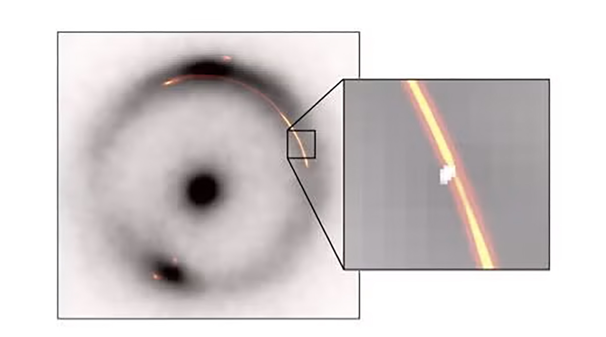 How the strange object was found. In this image, the black ring and central dot are infrared light from a distant galaxy being distorted by the gravity of a smaller, closer object. Orange/red shows radio waves from the same object. The inset shows a pinch caused by another, much smaller, dark gravitational lens (white blob). Credit: Devon Powell, Max Planck Institute for Astrophysics