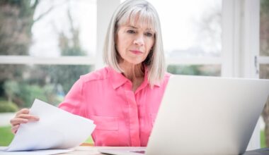 Person holding document and staring at laptop.