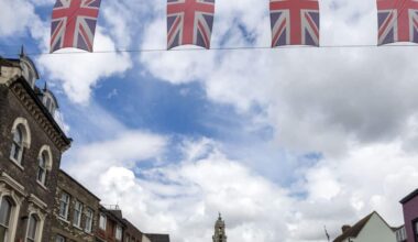 Union Jack bunting flags in a line strung across High Street in town center of Colchester, Essex, England, UK