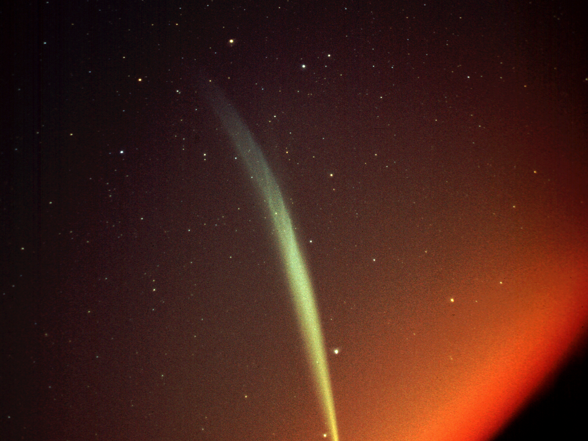 A streak of colored light in front of a red space background