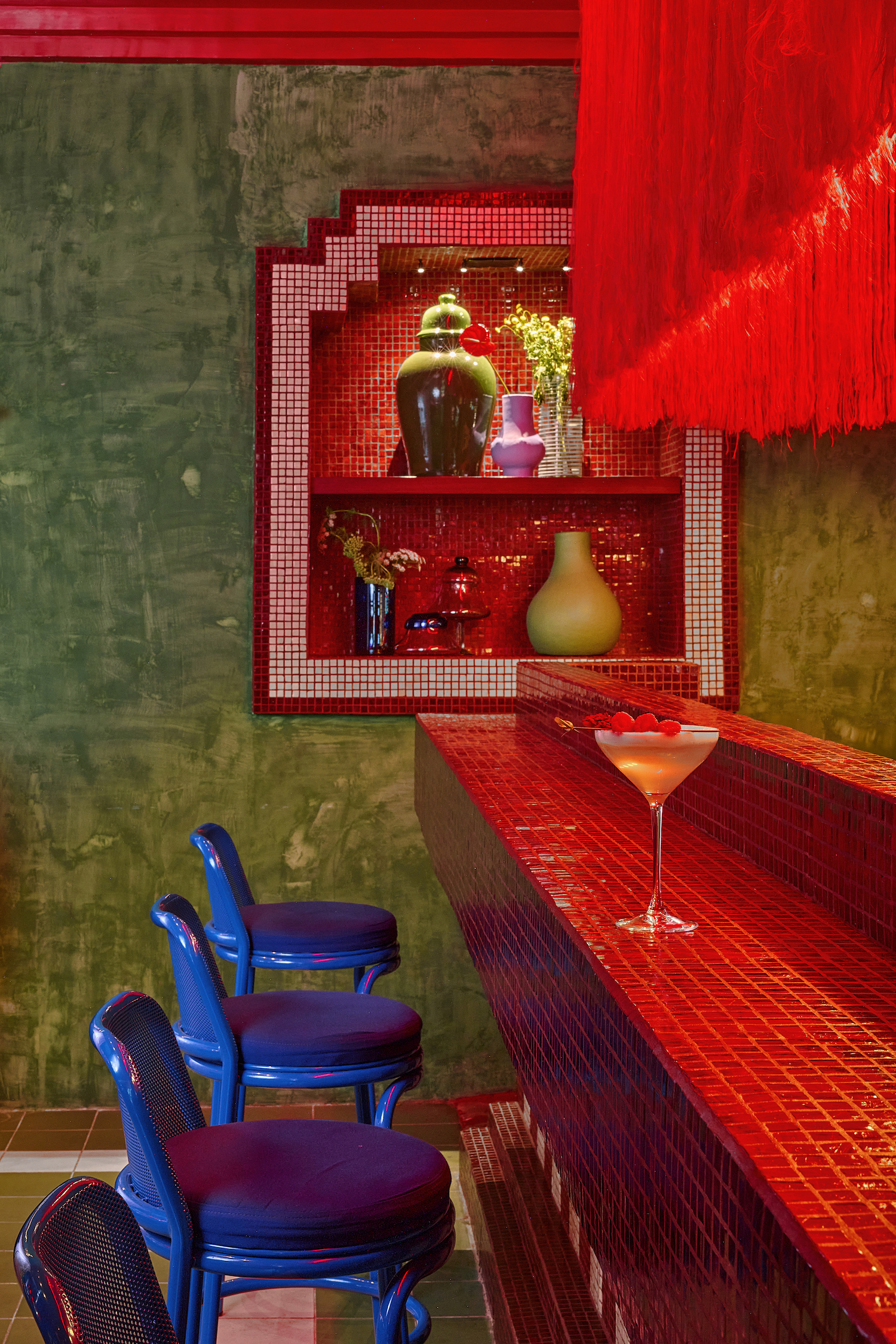 A bright red bar with azure bar stools and pistachio walls