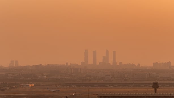 a skyline of tall buildings in the distance with smog in the air