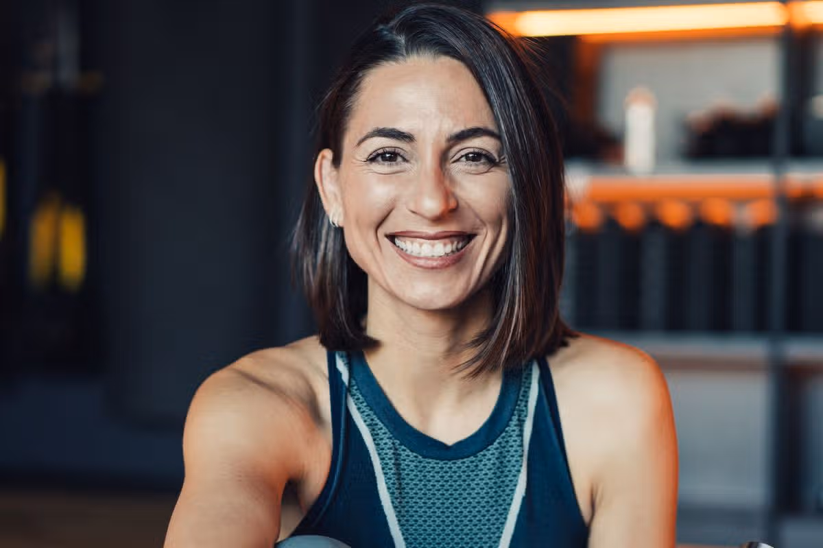 Portrait of a beautiful young sporty woman sitting on the floor in the gym and looking at camera.