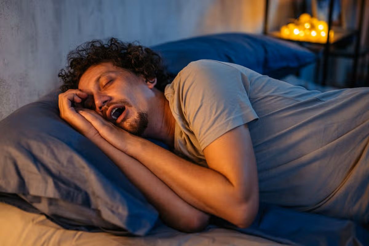 Handsome mid-adult man sleeping in the bed at night in his bedroom. Snoring and having breathing problems.
