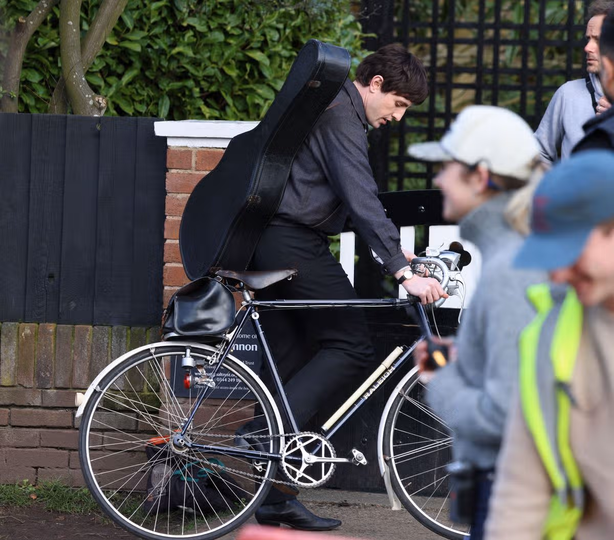 Actor Paul Mescal getting on his bike as Paul McCartney while filming at John Lennon's childhood home in Liverpool
