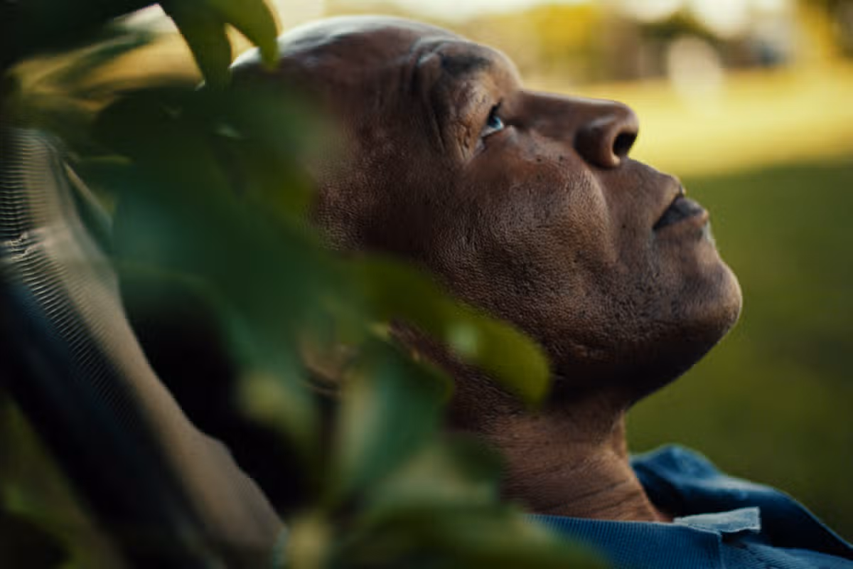 A man lays in a garden looking sad
