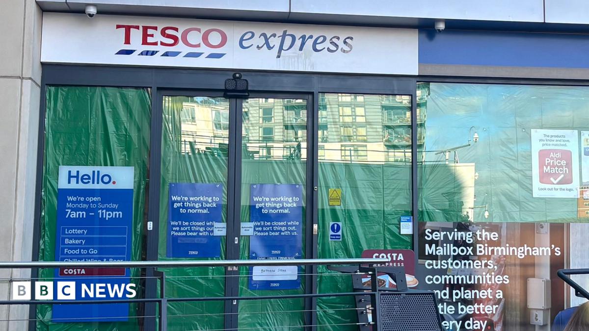 A photo of a Tesco Express shop with green plastic sheets on the inside of the windows.