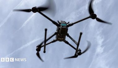 A laser scanning drone is seen flying against a blue sky.