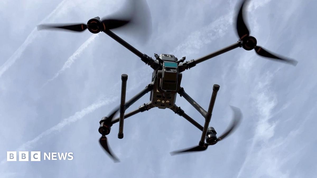 A laser scanning drone is seen flying against a blue sky.