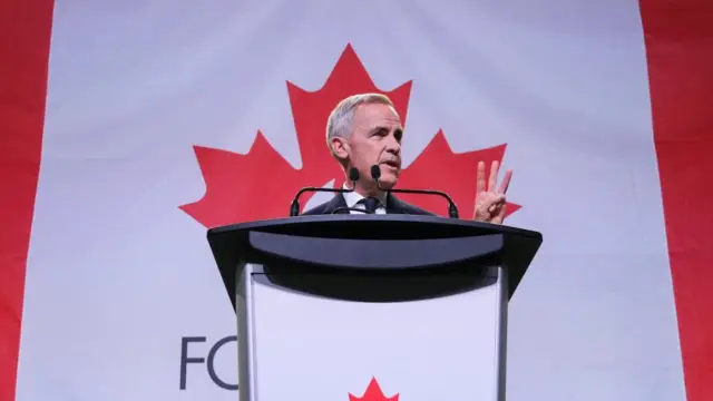 Mark Carney at a podium in front of a massive red and white Canadian flag