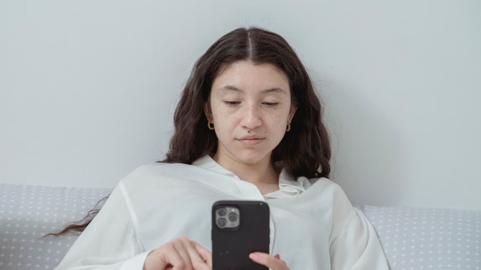 Woman looking at her phone with a poker face