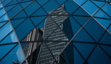Modern office buildings in the City of London reflected in the geometric glass facade of another skyscraper.