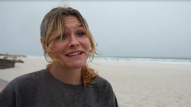 Haille looks at the camera as she speaks standing in front of a beach